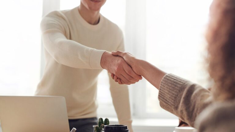 Lokale linkbuilding Zoetermeer: twee ondernemers geven elkaar een hand aan een werktafel met laptop